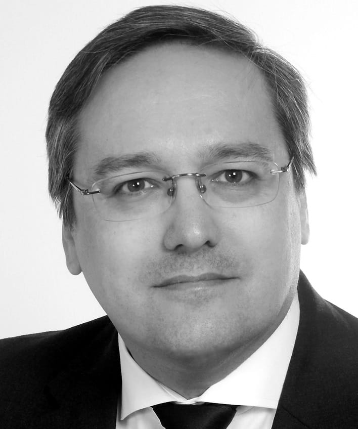 black and white headshot of Tim Lane wearing a suit against a white background