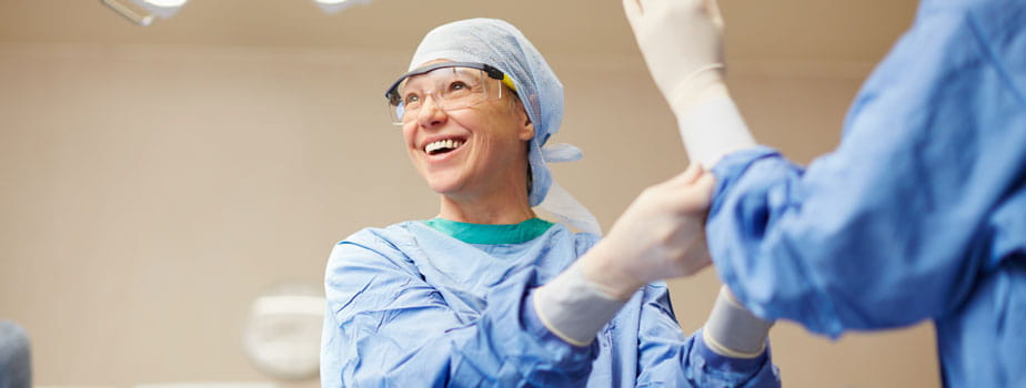 Female surgeon gloving surgical colleague