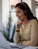A woman smiling while looking at a laptop.