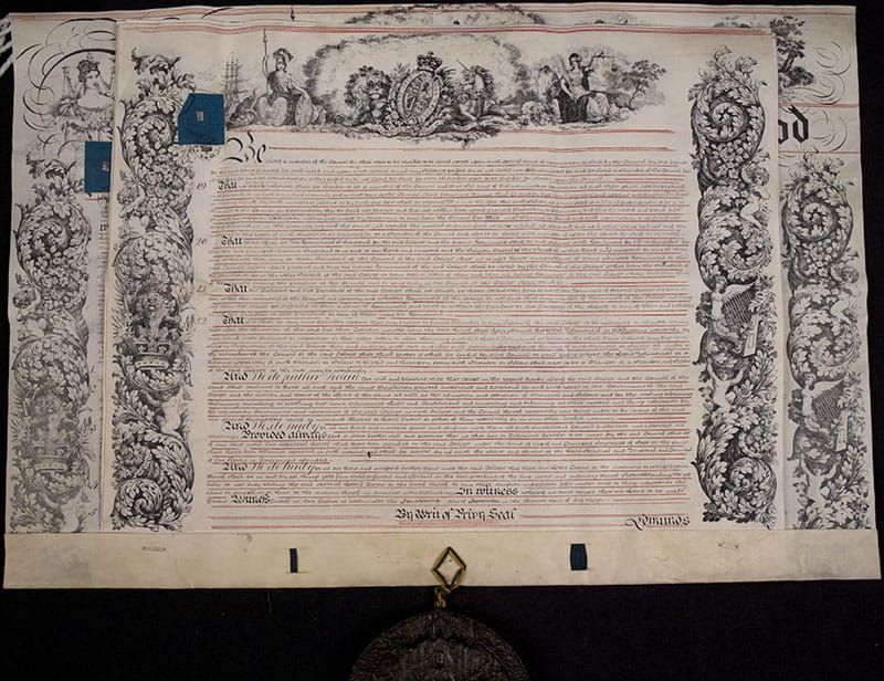 A formal document with elaborate decorations and calligraphy, with an attached wax seal